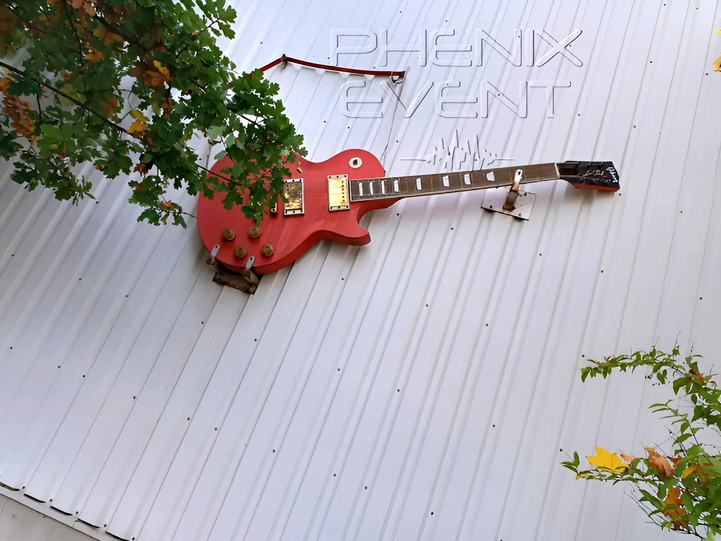 une guitare Gibson Les Paul grand format accrochée a une façade