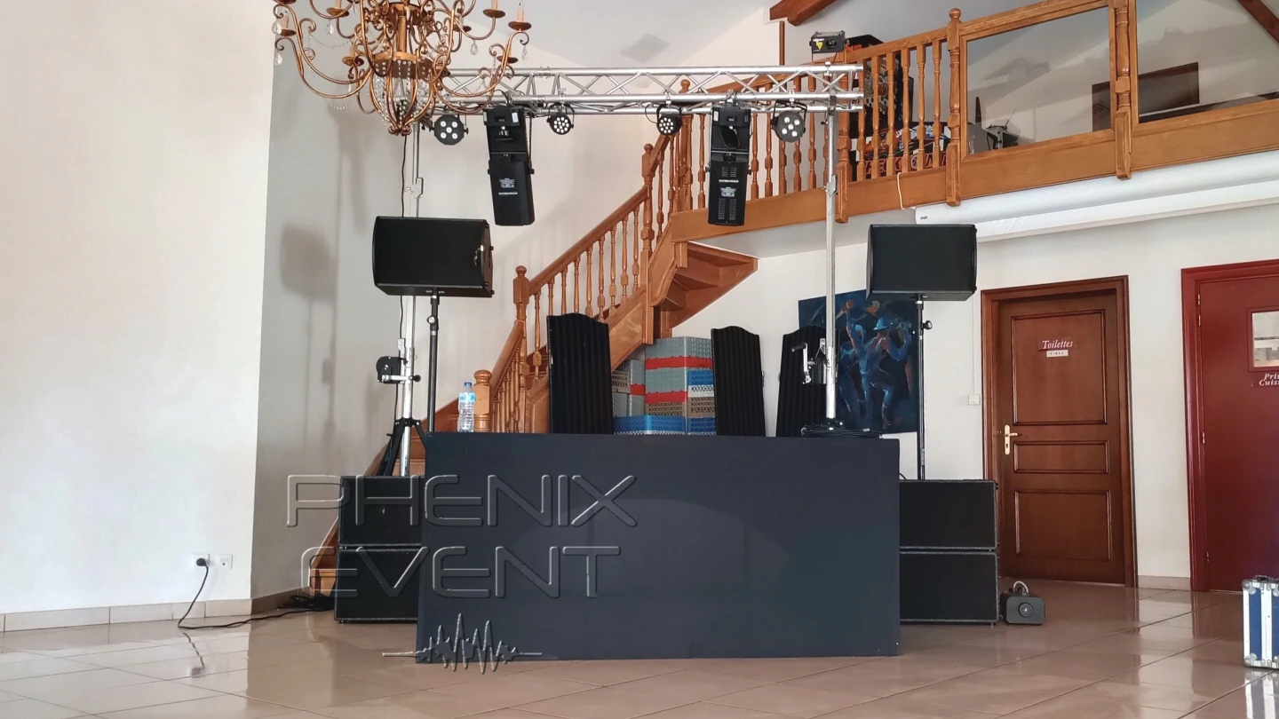 les enceintes et caissons de basses du pack sono 3000w stack sont disposés de parts et d'autres de la table pour dj. Une structure alminium garnis de jeux de lumière est hissée et surplombe le tout. caissons de basses sont placés