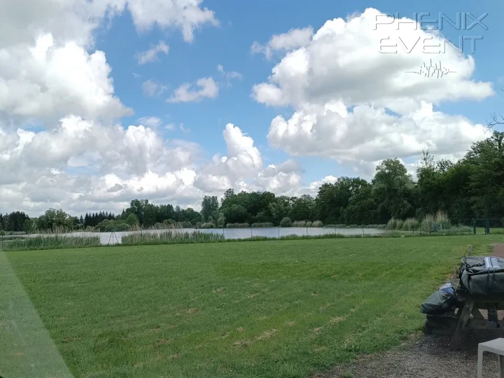 Vue sur l'étang clôturé et la forêt depuis le parking de la salle des fêtes de Vittoncourt