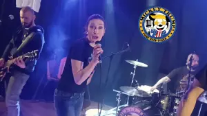 Mickey Trump interprétant "Take On Me" en live sur la scène de la mairie de Fillières. Marine, la chanteuse du groupe, tient en main un micro et semble très contente d'interpréter cette chanson