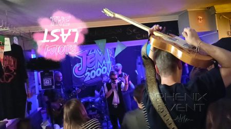 Au premier plan, Hervé, le chanteur, joue de la guitare en la tenant au dessus de sa tête, au second plan, un membre du public est invité à chanter