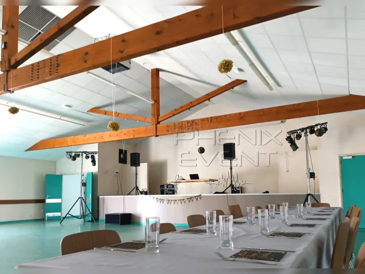 Salle des fêtes de Pontpierre, tables décorées, système son sur la scène et jeux de lumière au sol