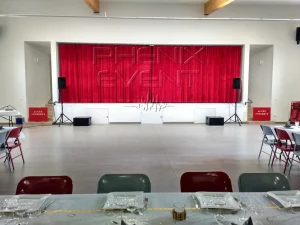 Sono 2000W Phenix Event louée et installée devant la scène, munie de rideaux rouges, de la salle des fêtes de Solgne.