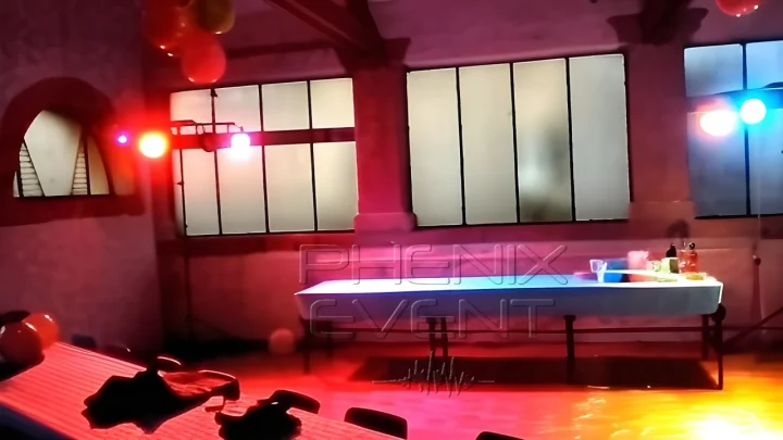 deux trépieds équipés de spots lumineux installés à côté des tables colorent la piste de danse de la salle des fêtes