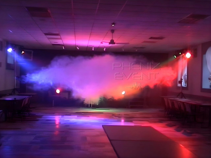 un nuage de brume compact et coloré généré par la machine à fumée du pack fête 1 s'étale se forme sur la piste de danse, les projecteurs éclairent la salle