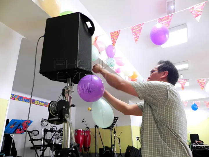 Client accrochant des ballons sur les enceintes Phenix Event pour l'anniversaire