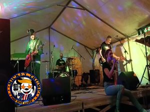 le groupe mickey trump interprétant Cover Me In Sunshine, la chanteuse est assise sur le nez de scène