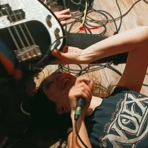 couverture du single montrant la chanteuse allongée sur le sol, tenant un micro et une guitare basse